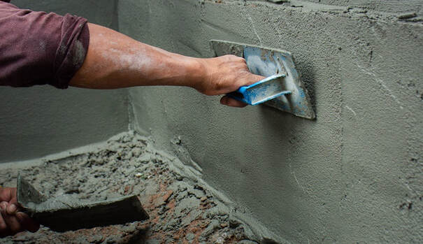 Concrete contractor repairing a section of concrete wall with fresh cement